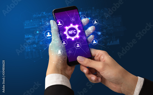 Female hand holding smartphone with NFC abbreviation, modern technology concept photo