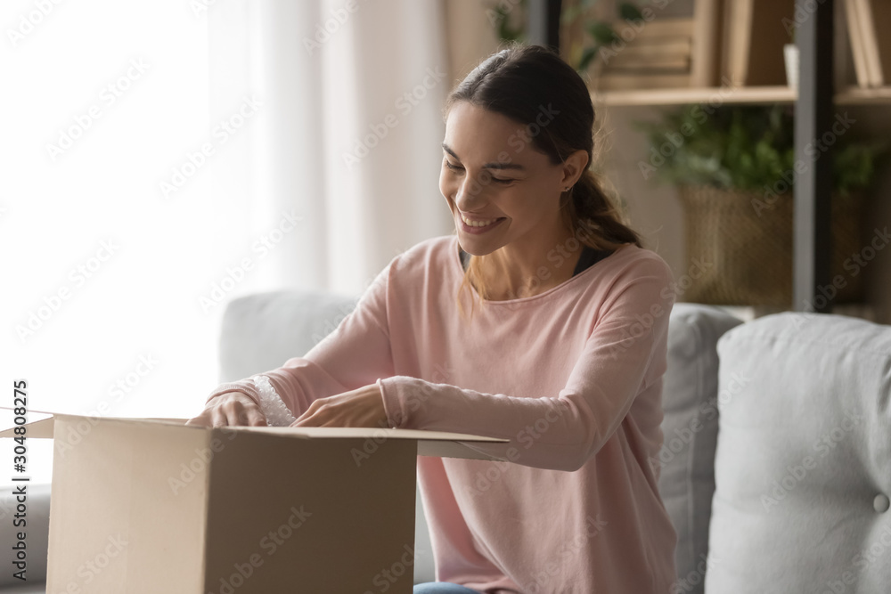 Happy female client open cardboard package at home Happy female client open cardboard package at home