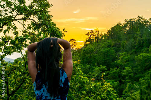 A woman enjoying a beautiful sunrise over the forest, Mussoorie, Uttarakhand, India photo