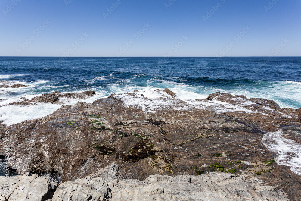 Rebentação das ondas do oceano no rochedo da costa.
