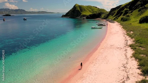 Aerial view of attractive woman walking at pink beach, Padar islands, Indonesia. photo
