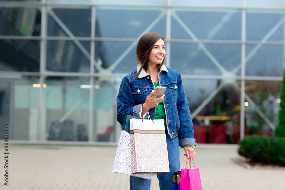 Happy brunette woman with shopping bags and cellphone enjoying in shopping. Shopping, lifestyle concept