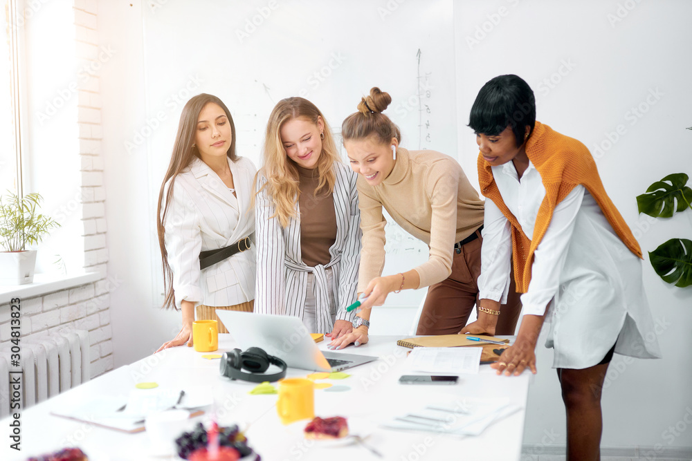 in wait of results of competition. young caucasian and african people female looking at laptop in waiting. togetherness concept in wait of results of competition. young caucasian and african people female looking at laptop in waiting. togetherness concept