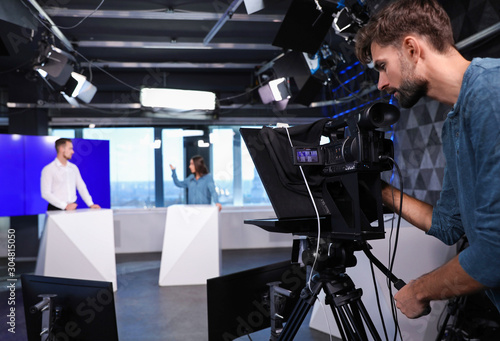 Fotografie Presenters and video camera operator working in studio