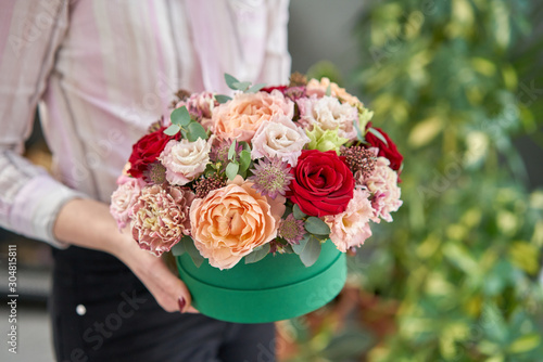 European floral shop. Floral bunch in round box. Bouquet of beautiful Mixed flowers in woman hand. Excellent garden flowers in the arrangement , the work of a professional florist.