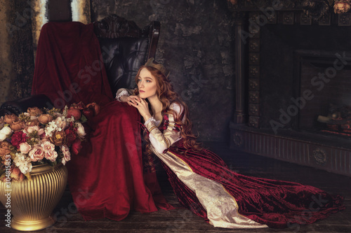 Redheaded woman with crown and old-fashioned  dress in flowers