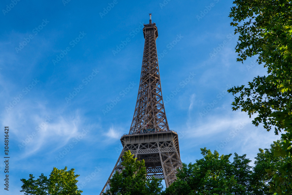 Paris Eiffel Tower and bright blue sky in Paris, France. Eiffel Tower is one of the most iconic landmarks of Paris. Copy space for your text.