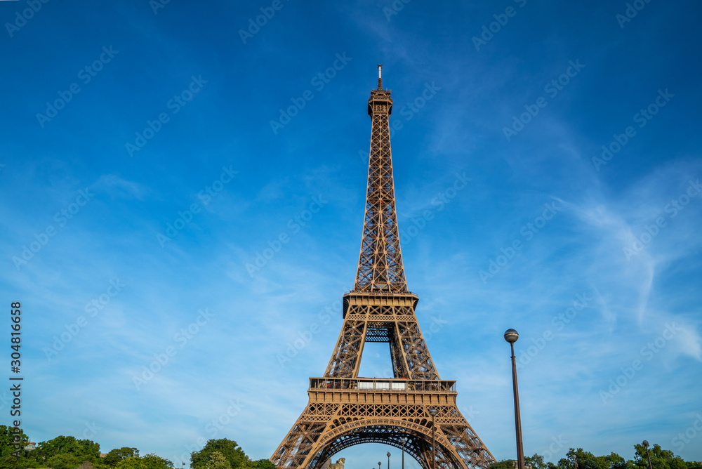 Paris Eiffel Tower and bright blue sky in Paris, France. Eiffel Tower is one of the most iconic landmarks of Paris. Copy space for your text.