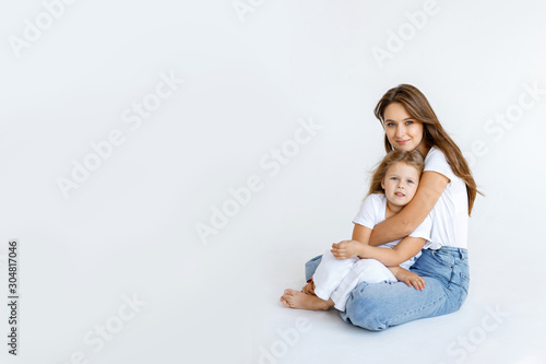 Happy mom and daughter cuddling on a white background. Happy family concept
