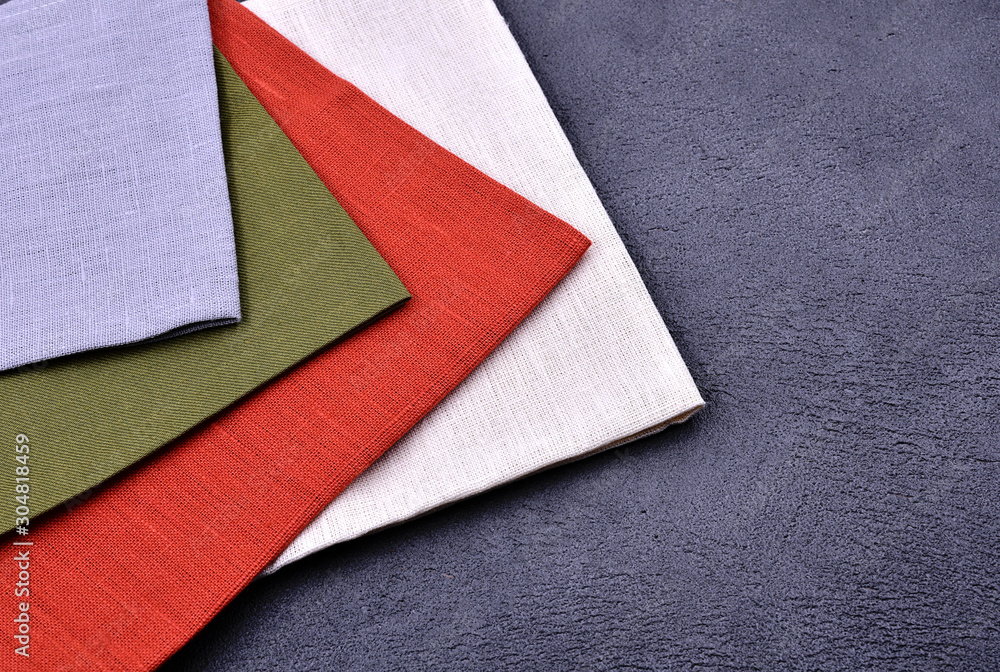 Fototapeta premium Multicolored linen towels on a dark stone background.