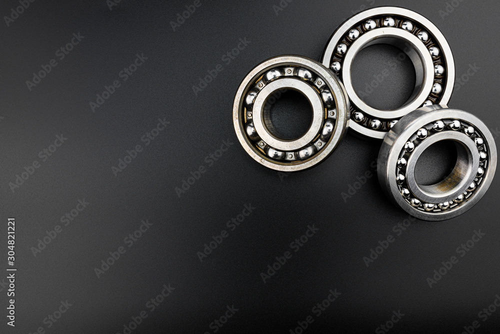 Ball bearing lying on a black background with copy space on the left side, flat view from above. Ball bearing lying on a black background with copy space on the left side, flat view from above.