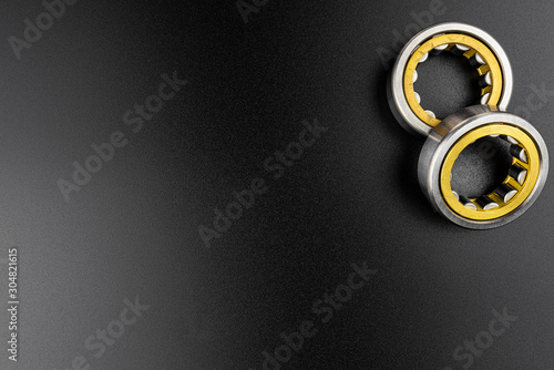 Ball bearing lying on a black background with copy space on the left side, flat view from above.