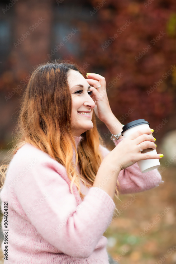 White female, Caucasian woman sitting on rock, holding coffee. Smiling and happy. Autumn, Fall. White female, Caucasian woman sitting on rock, holding coffee. Smiling and happy. Autumn, Fall.
