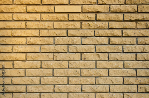 Rustic yellow brick wall. The edge of the brick has been chipped. The upper left corner of the wall is lit by the setting sun. Background. Texture.