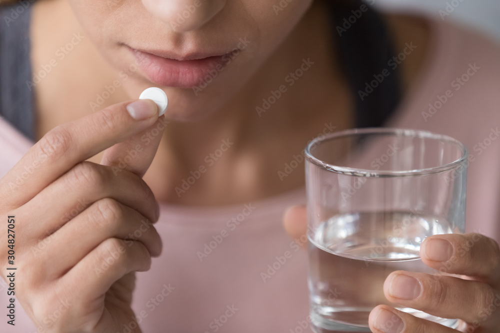 Close up of hesitant female considering taking medicine Close up of hesitant female considering taking medicine