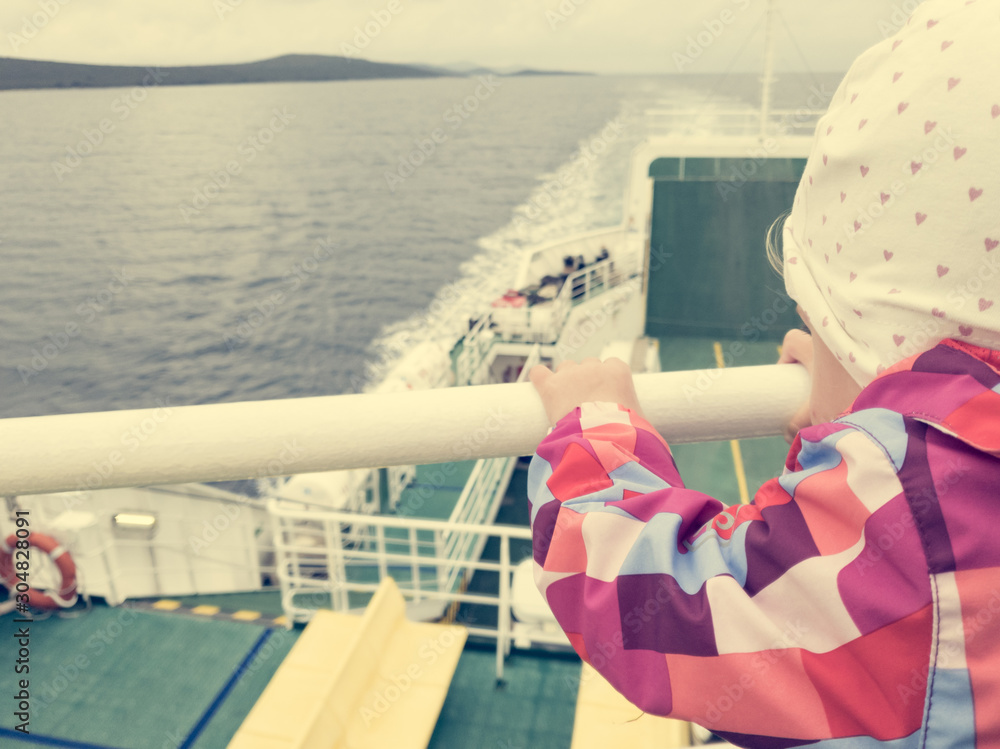Obraz premium Rear view of a cute girl enjoying a ferry ride in cloudy weather.