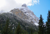 Clouds hang on the peaks and forests of the Tetons after an Autumn storm, but they are giving way to the blue sky.