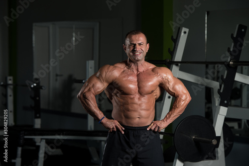 Mature Bodybuilder Standing In The Gym