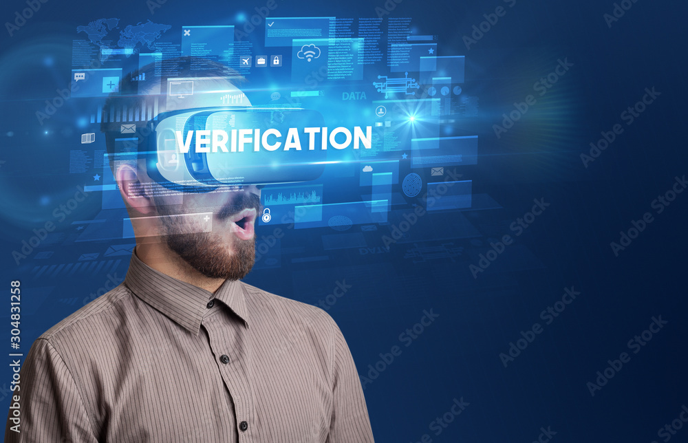 Businessman looking through Virtual Reality glasses with VERIFICATION inscription, innovative security concept Businessman looking through Virtual Reality glasses with VERIFICATION inscription, innovative security concept