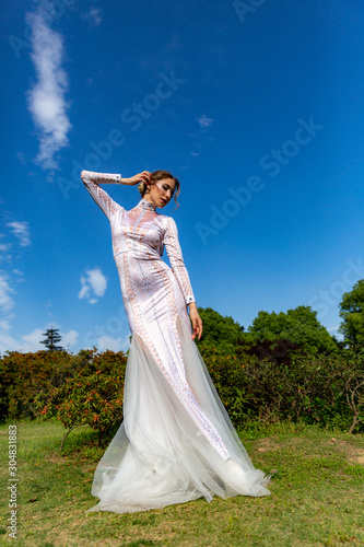 girl in a white long dress on a background of blue sky with white clouds © spaceneospace