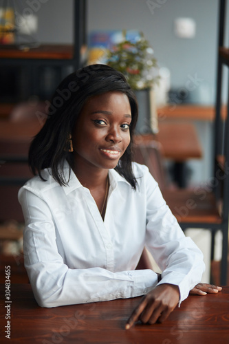 Portrait of a successful dark-skinned businesswoman and entrepreneur in her office, enjoying corporate lifestyle. Cheerful and confident in her future in business industry and career development.