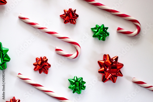 Christmas decorative background with candy cane red and white and christmas bow on the white background. Christmas Holiday Concept. Copy space. Top view.