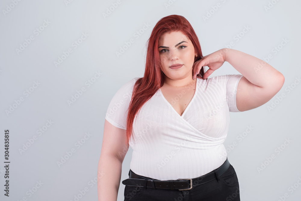 Young obese woman in casual clothes on a white background in the studio. Bodypositive and improper nutrition. Young obese woman in casual clothes on a white background in the studio. Bodypositive and improper nutrition.
