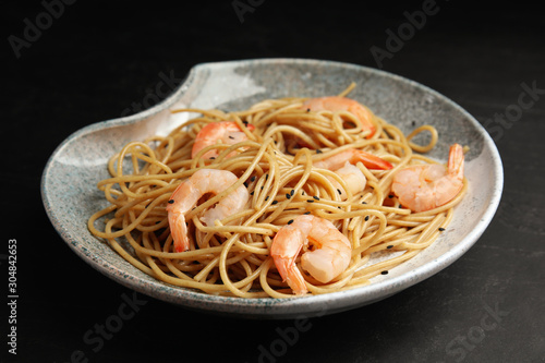 Plate of tasty buckwheat noodles with shrimps on black table