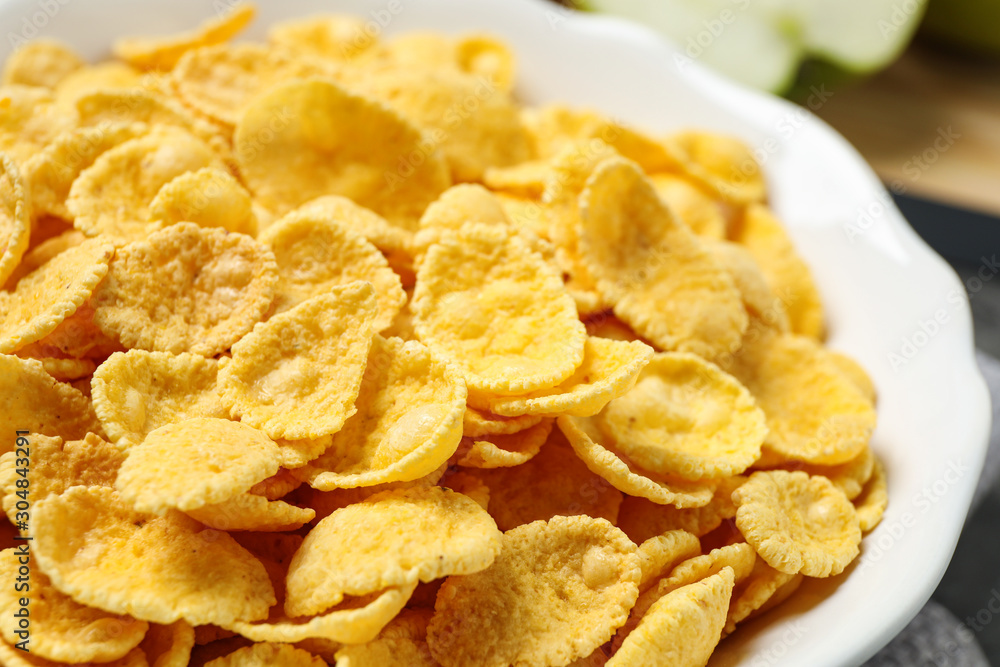 Tasty crispy corn flakes in bowl, closeup