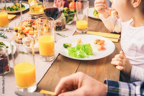 Little girl eats at a table with her family