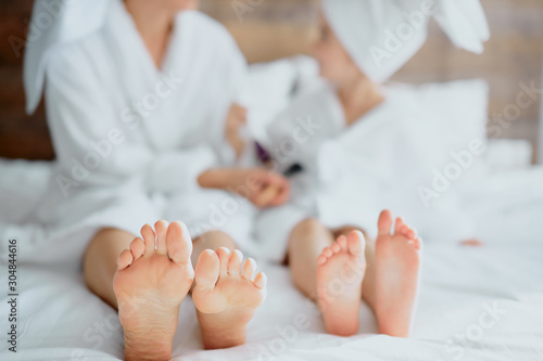 young woman and little child's foot, lying on bed together in bathrobe and towel