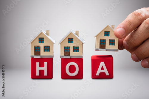 Person Placing The Miniature Houses On Red Hoa Blocks
