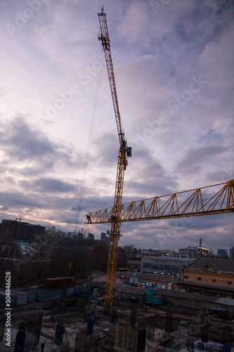 Construction site and cranes in the early evening. Workers on the crane and construction site