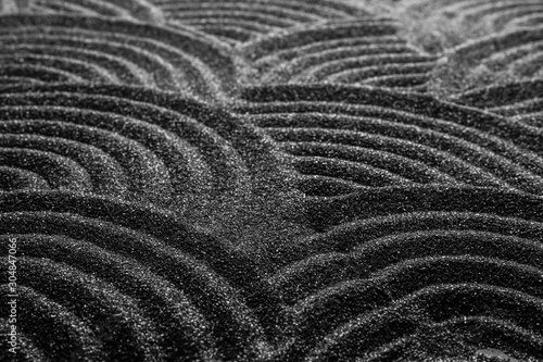 Black sand with beautiful pattern, closeup. Zen concept