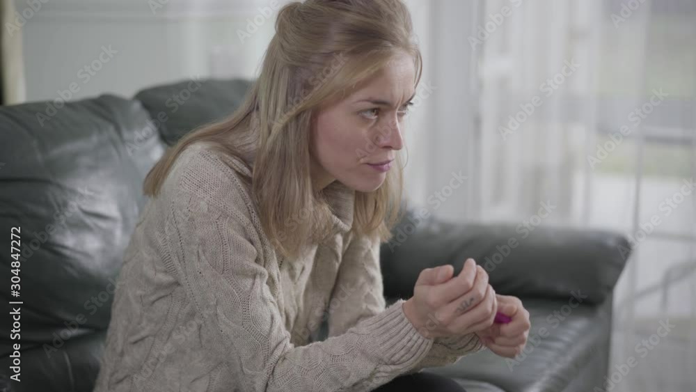 Side view of Caucasian woman with brown eyes holding affirmative pregnancy test and thinking. Woman with snake tattoo on finger deciding what to do with unexpected pregnancy. Side view of Caucasian woman with brown eyes holding affirmative pregnancy test and thinking. Woman with snake tattoo on finger deciding what to do with unexpected pregnancy.