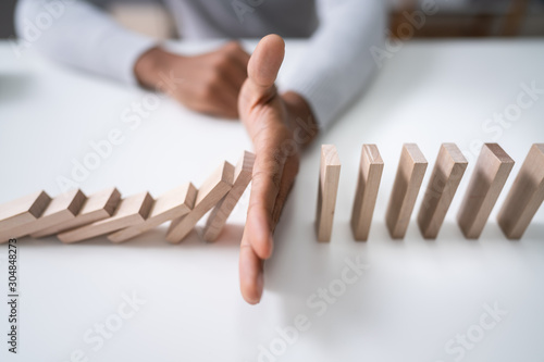 Foto Businessman Stopping The Effect Of Domino
