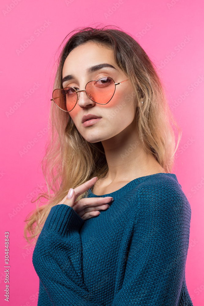 Romantic blonde-haired girl in trendy heart glasses posing with shy smile. Studio close-up portrait Romantic blonde-haired girl in trendy heart glasses posing with shy smile. Studio close-up portrait