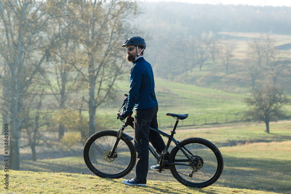 Obraz premium Cyclist in pants and fleece jacket on a modern carbon hardtail bike with an air suspension fork rides off-road. 