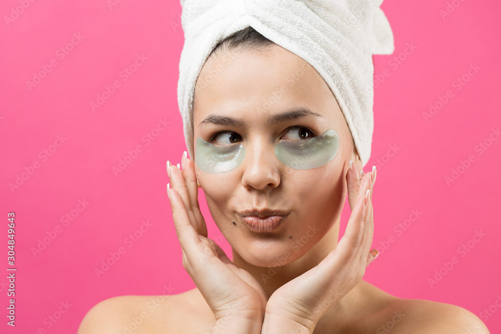 Young beautiful girl in a white towel on his head wears collagen gel patches under her eyes. Mask under eyes treatment face. Young beautiful girl in a white towel on his head wears collagen gel patches under her eyes. Mask under eyes treatment face.