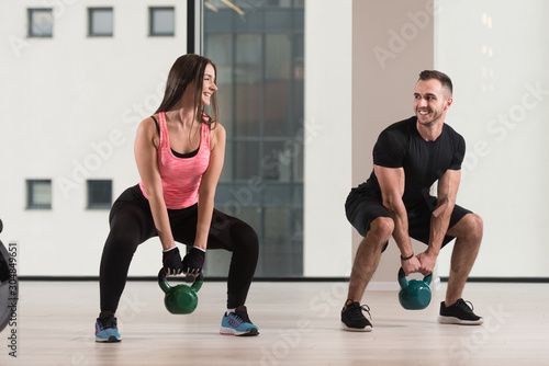 Healthy Young Couple Doing Exercise With Kettle Bell