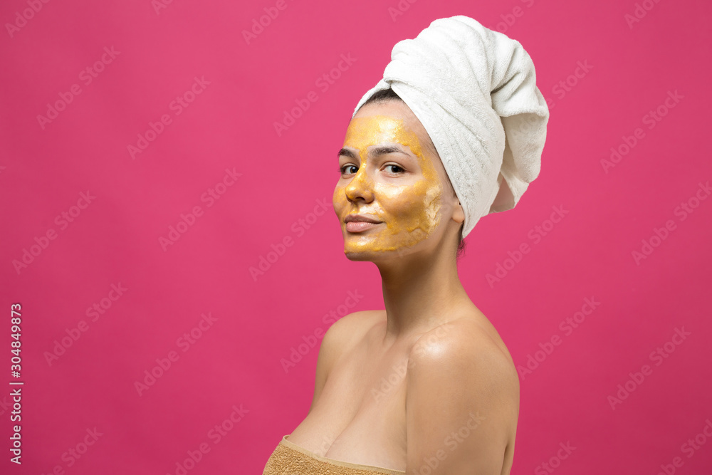 Beauty portrait of woman in white towel on head with gold nourishing mask on face. Skincare cleansing eco organic cosmetic spa relax concept. Beauty portrait of woman in white towel on head with gold nourishing mask on face. Skincare cleansing eco organic cosmetic spa relax concept.