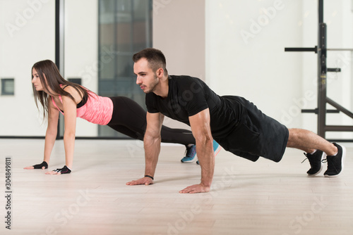 Young Couple Doing Pushups In The Gym