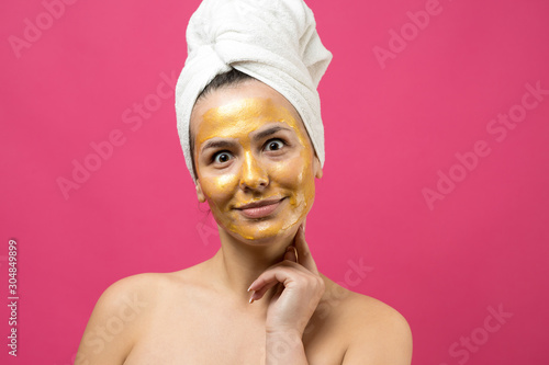 Beauty portrait of woman in white towel on head with gold nourishing mask on face. Skincare cleansing eco organic cosmetic spa relax concept. 