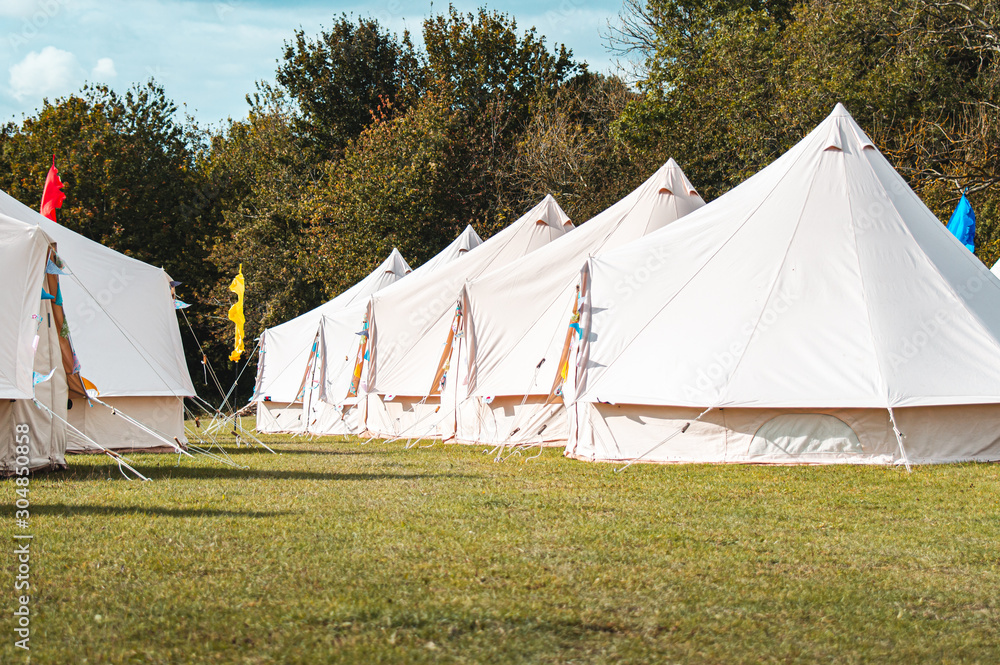 Light creme canvas waterproof tent in a green field on a nice and hot summer day. Blue Clouds, green grass, Child festival tent. Light creme canvas waterproof tent in a green field on a nice and hot summer day. Blue Clouds, green grass, Child festival tent.