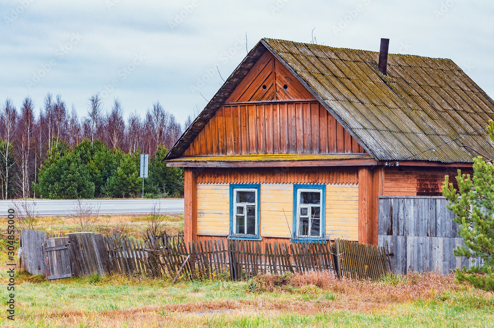 Fototapeta premium Abandoned ancient wooden house by the road.