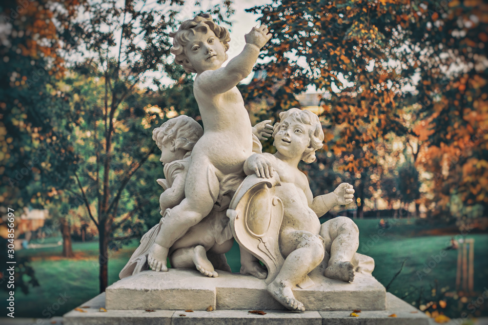 Sculpture of three kids or cherubes at the Burggarten in Vienna during autumn evening