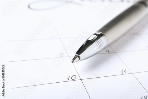 Pen on calendar page, closeup. Planning concept