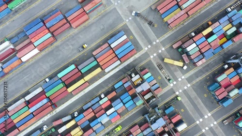 JAKARTA, Indonesia - November 19, 2019: Top down view of containers and trucks in Tanjung Priok industrial port. Shot in 4k resolution from a drone flying forwards photo