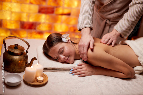 Young lady of caucasian appearance receiving back massage by professonal female hands in spa salon. Leisure photo