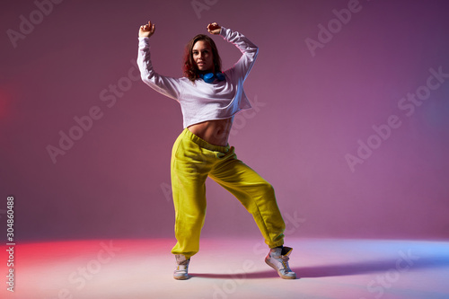 Fotografia Athletic modern style dancer performing dance element, standing on stage of scho